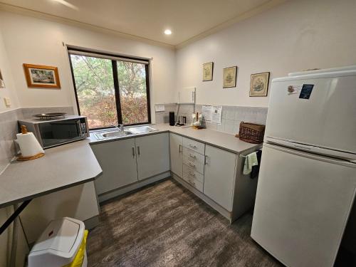 a kitchen with a white refrigerator and a window at Barossa Country Cottages in Lyndoch