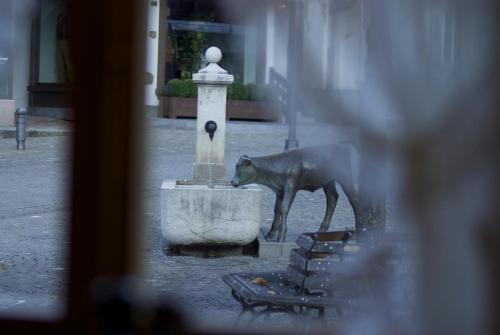 a statue of a dog standing next to a fountain at Posthotel Rössli in Gstaad
