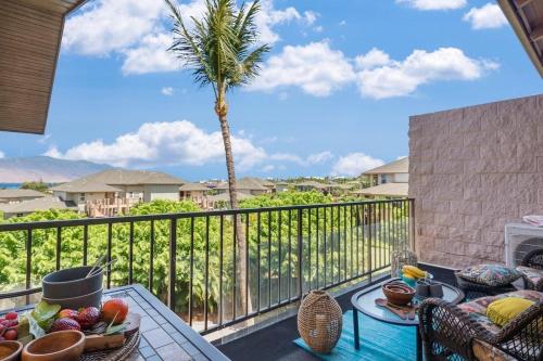 a balcony with a table and a palm tree at Kihei Alii Kai C405 · KAK C405 Updated 2BD Condo Across Beach w in Kihei