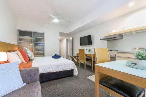 a living room with a bed and a kitchen at Darwin City Centre Studio Pool, Gym & Parking in Darwin