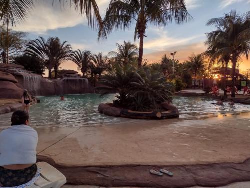 une personne assise sur un banc dans une piscine d'un complexe hôtelier dans l'établissement Apartamento Barretos Country Resort, à Barretos