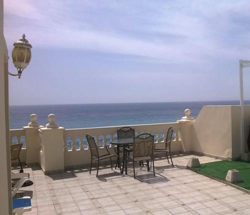 un patio con mesa, sillas y el océano en Apartamentos Balcon de Carabeo, en Nerja