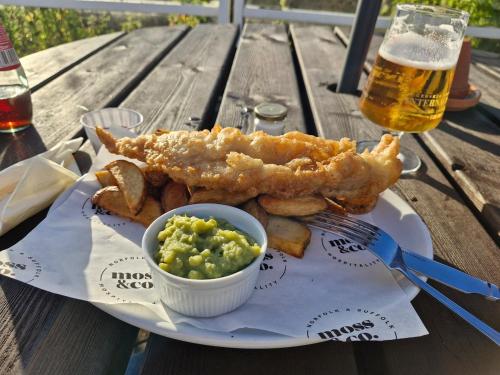 a plate of food with fish and chips and a glass of beer at Modern Newly Renovated Home on the Broads in Lowestoft