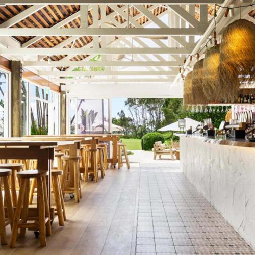 a restaurant with wooden tables and chairs and a bar at BreakFree Aanuka Beach Resort in Coffs Harbour