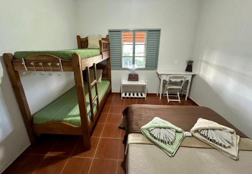 a small room with two bunk beds and a table at Casa no Vale da Babilônia Serra da Canastra in Delfinópolis