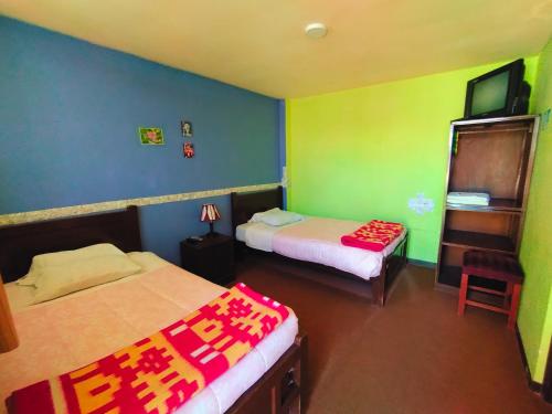 two beds in a room with green and blue walls at La Casa del Manzano in Puno