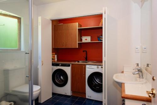 a bathroom with a washing machine and a sink at Tropical Escape near the beach with fire-pit & spa in Bowentown