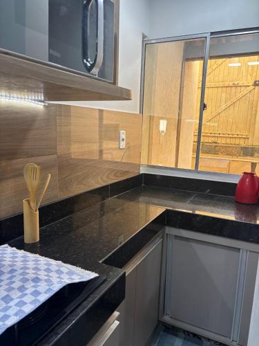 a kitchen with a black counter top and a window at Casa Praia da Fonte in Guarapari