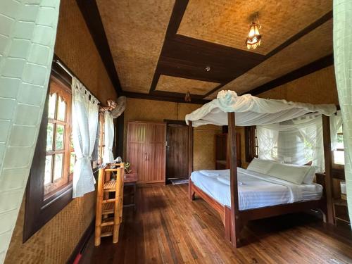 a bedroom with a bed and a ladder in a room at Bambu Huts in Ban Tai