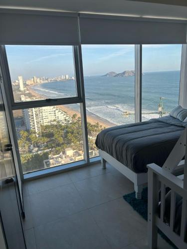 a bedroom with a bed and a view of the ocean at Beachfront Apartment in Mazatlán