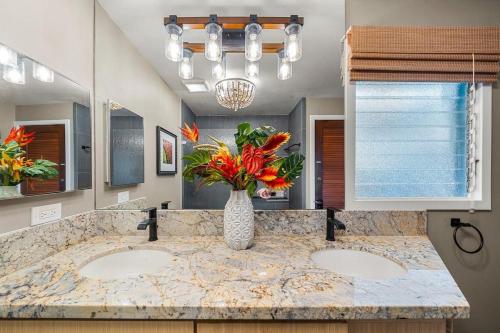 a bathroom with two sinks and a vase with flowers at International Colony Club 28 · ICC 28 Remodeled 2BD Cottage in K in Lahaina