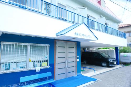 a blue building with a garage and a balcony at Osaka English House in Hirakata