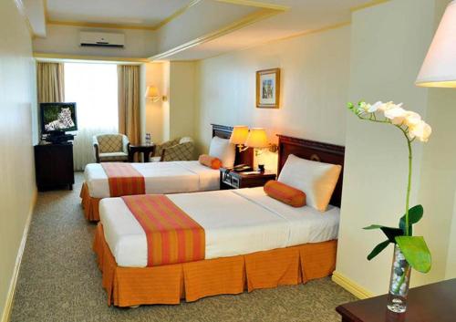 a hotel room with two beds and a living room at Networld Hotel Spa and Casino in Manila