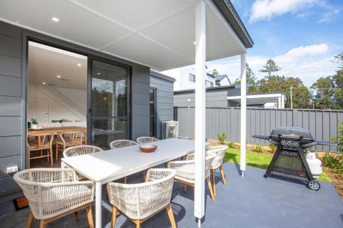 a patio with a white table and chairs and a grill at Kirkland - Pet Friendly - 5 Mins Walk to Beach in Culburra Beach