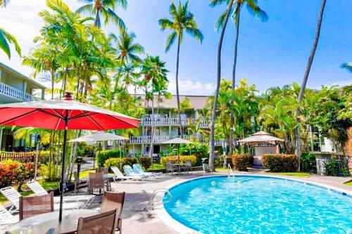 una piscina con sedie, ombrellone e palme di Kona Islander Inn Condos a Kailua-Kona