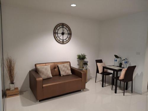 a living room with a couch and a table with a clock at Condo Baan klang Hua Hin city center in Hua Hin