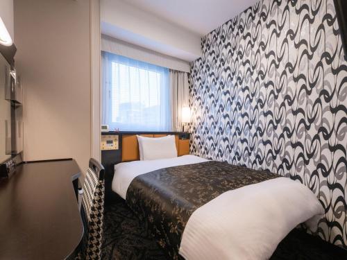 a hotel room with a bed and a patterned wall at APA Hotel Nagoya Ekimae Minami in Nagoya