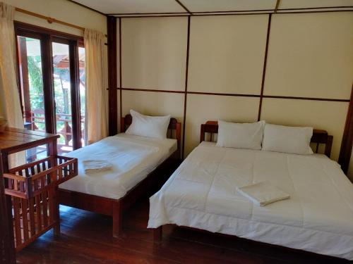 a bedroom with two beds and a table and windows at Bungalows Le Jardin VANGVIENG in Vang Vieng