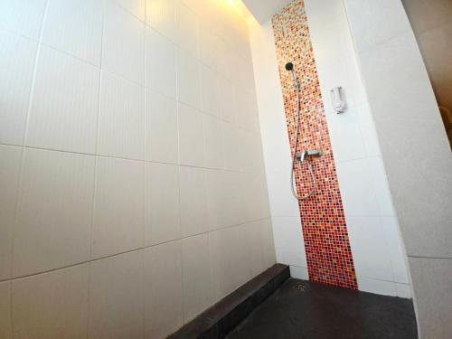 a bathroom with a shower with a red tile wall at Save Hotel เซฟ โฮเทล in Chon Buri