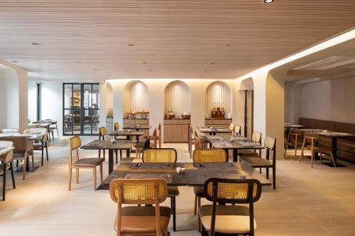 a restaurant with tables and chairs in a room at Away Bangkok Sukhumvit in Bangkok