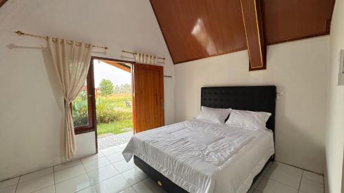 Schlafzimmer mit einem Bett und einer Tür zum Fenster in der Unterkunft Teras Alam in Karangjati