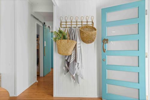 a hallway with a blue door and hanging baskets at The Chill - Your Dreamy Waterfront Escape in Sanctuary Point