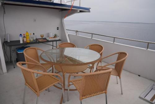 een glazen tafel en stoelen op een cruiseschip bij Iate AmazonHunter in Manaus