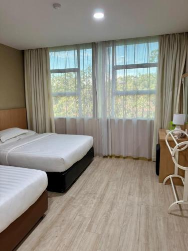 a hotel room with two beds and a desk and windows at Labuan Avenue Hotel in Victoria
