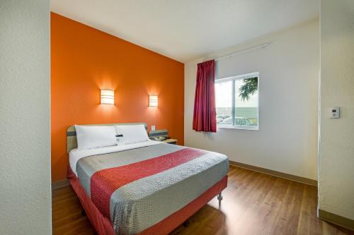 a bed in a room with an orange wall at Motel 6-Brampton, ON - Toronto in Brampton