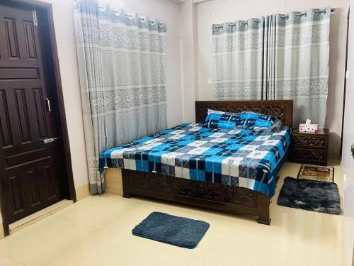 a bedroom with a bed with a blue plaid blanket at Bashundhara Luxury 3BR Apartment Near Evercare in Dhaka