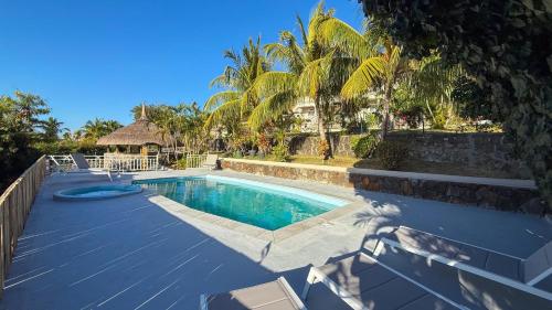 a swimming pool next to a resort with palm trees at LAKAZ DEL VISTA - Luxurious new apartments with panoramic sea views, pool & garden retreat in Tamarin