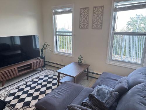 a living room with a couch and a flat screen tv at Cozy apartment with city skyline. Easy commute midtown Manhattan. in Jersey City