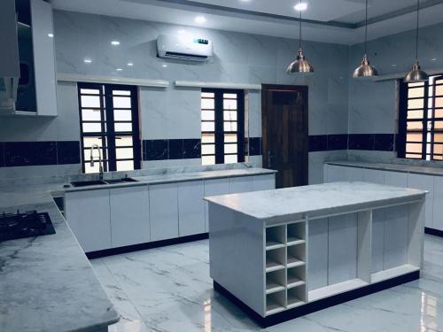 Sagisaにある5bedroom duplexの白いキャビネットと大きな島のある広いキッチンが備わります。