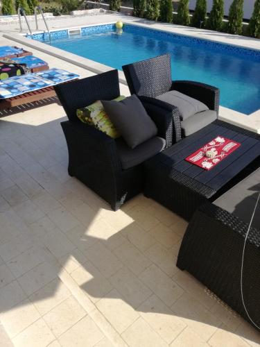 a patio with two chairs and a table next to a pool at Apartments Jankovic in Vodice