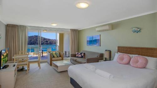 a bedroom with a large bed and a living room at Allure in Ettalong Beach