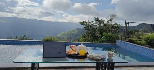 a laptop sitting on a table next to a pool at Koko House in Panchgani