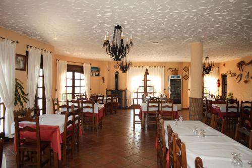 a dining room with tables and chairs and a chandelier at Hotel Restaurante Atalaya in Comares