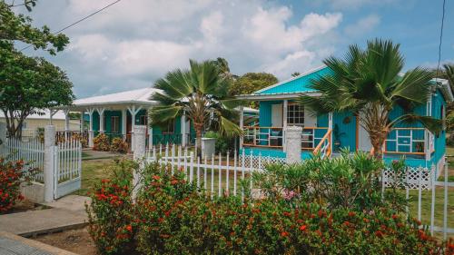 a blue house with a white fence and flowers at Ketlina Village in Providencia