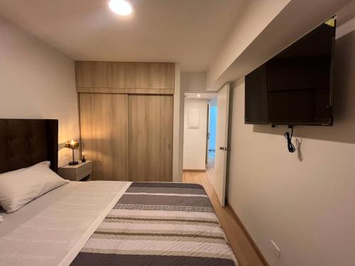 a bedroom with a bed and a flat screen tv at Apartamento Amoblado a un paso del parque de las aguas in Lima