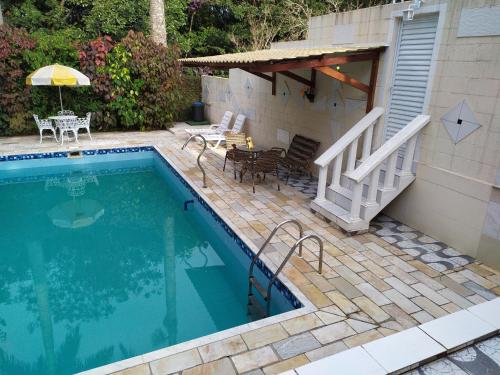 einen Pool neben einem Haus mit einem Tisch und Stühlen in der Unterkunft Pousada Flat Mobiliado com 70 m2 de Área Privativa com o máximo conforto in Atibaia