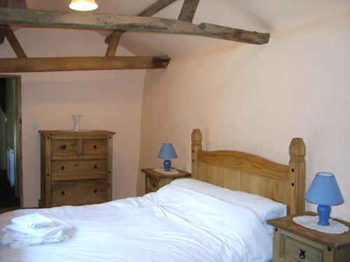 a bedroom with a bed with white sheets and blue lamps at Granary Cottage in Hardwick