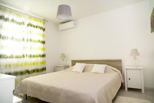 a white bedroom with a large bed and a window at Apartment Ema in Rogoznica