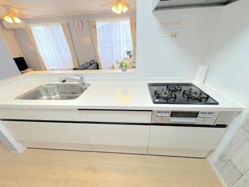 a white kitchen with a sink and a stove at THE FEEL ONNA 2 / Vacation STAY 18769 in Onna
