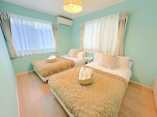 two beds in a room with blue walls and windows at THE FEEL ONNA 2 / Vacation STAY 18769 in Onna