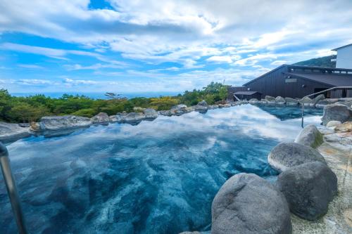 a swimming pool with rocks and blue water at YU-FURI Nasu-Takao Onsen Lodge in Nasu