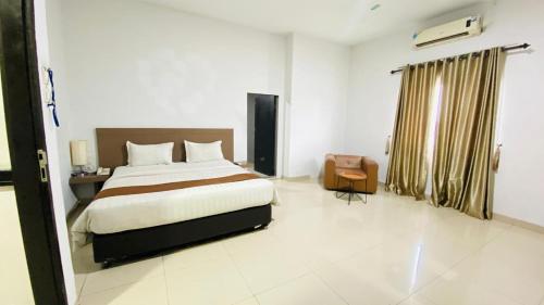 a bedroom with a bed and a chair in it at Saka Hotel Medan in Sunggal