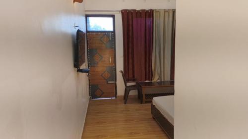 a room with a bed and a desk and a window at Munsyari camping zone & tracking snow hill in Munsyari