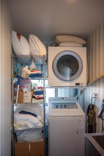 a laundry room with a washing machine and a microwave at Your Space Capsule Hotel Fuji Station in Fuji
