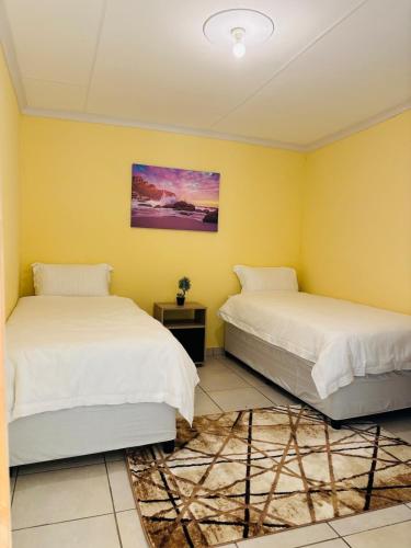 two beds in a room with yellow walls at Cozy 2 Bedroom near Kruger in Hectorspruit