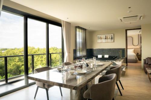 a dining room with a table and chairs and windows at Richmann Resort Hotel Hatyai in Hat Yai